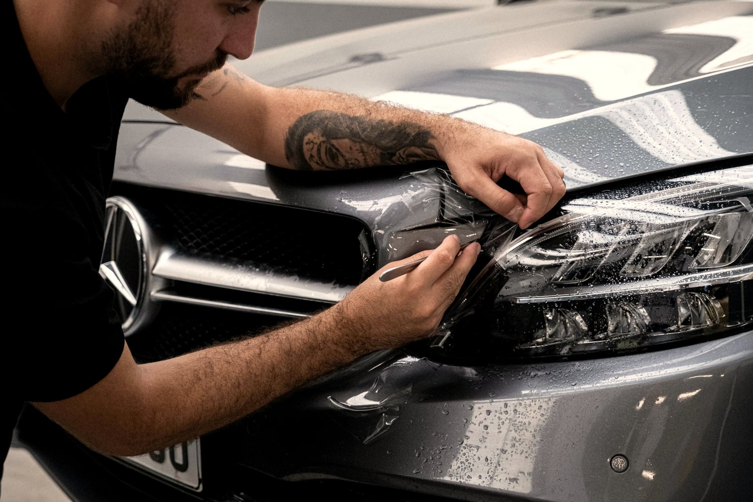 Auto detailer applying paint protection film to a car