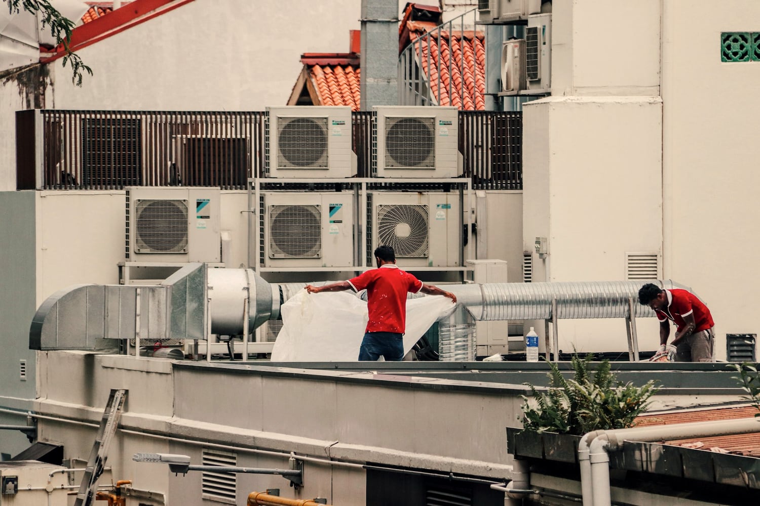 Two technicians servicing rooftop HVAC units