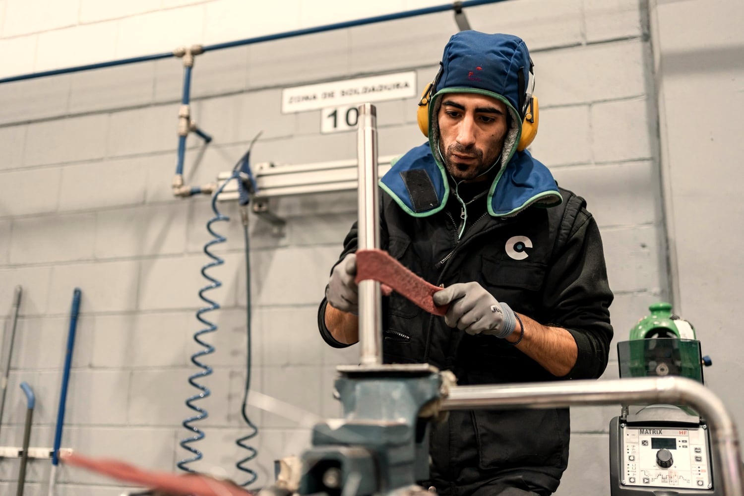 Metalworker at a bench in a shop, ear protection on